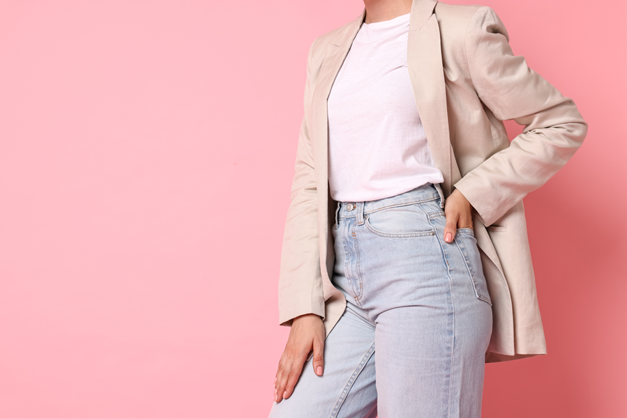 A woman wearing light blue jeans, a white t-shirt and beige blazer.